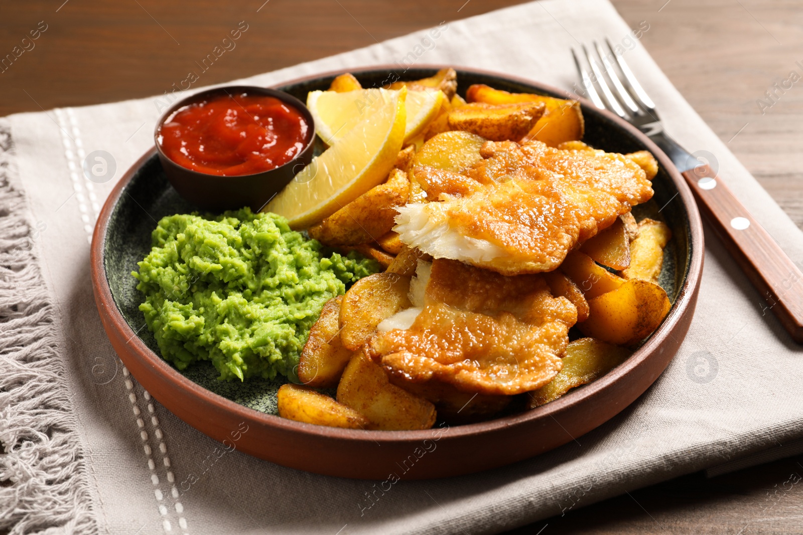 Photo of Plate with British traditional fish and potato chips on table