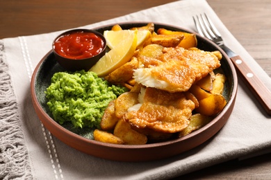 Plate with British traditional fish and potato chips on table