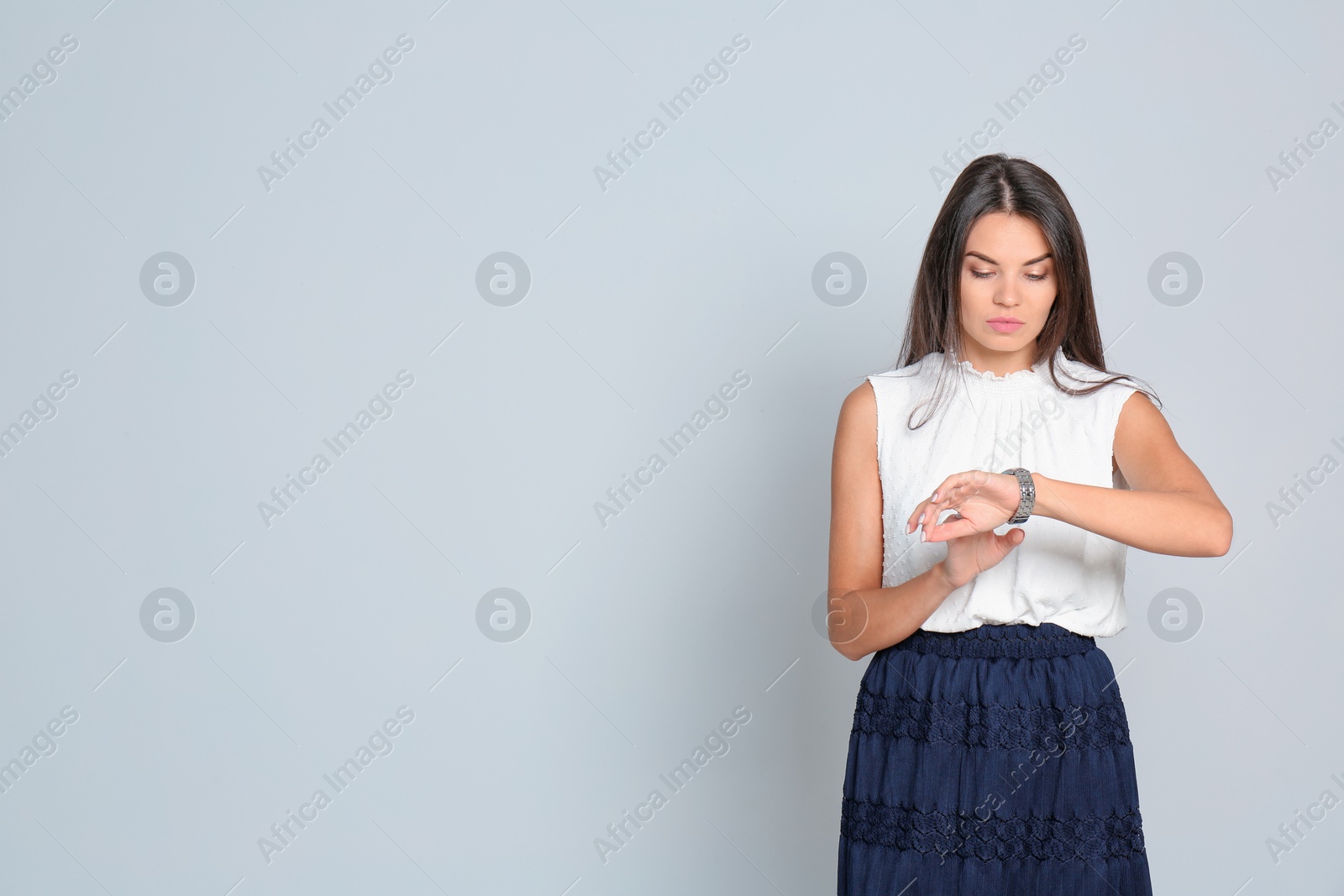 Photo of Beautiful woman with watch wearing office clothes against gray background. Space for text