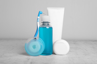 Photo of Dental floss and different teeth care products on light grey textured table