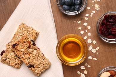Photo of Tasty granola bars served on wooden table, flat lay