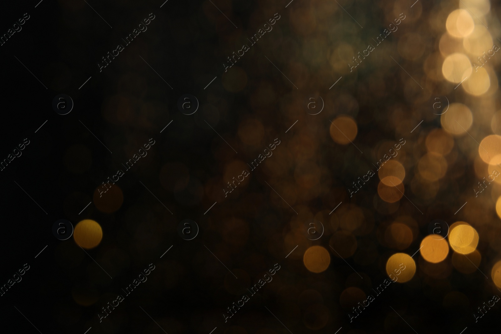 Photo of Blurred view of golden lights on black background. Bokeh effect