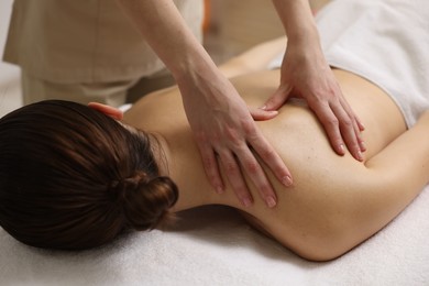 Photo of Woman receiving back massage on couch in spa salon