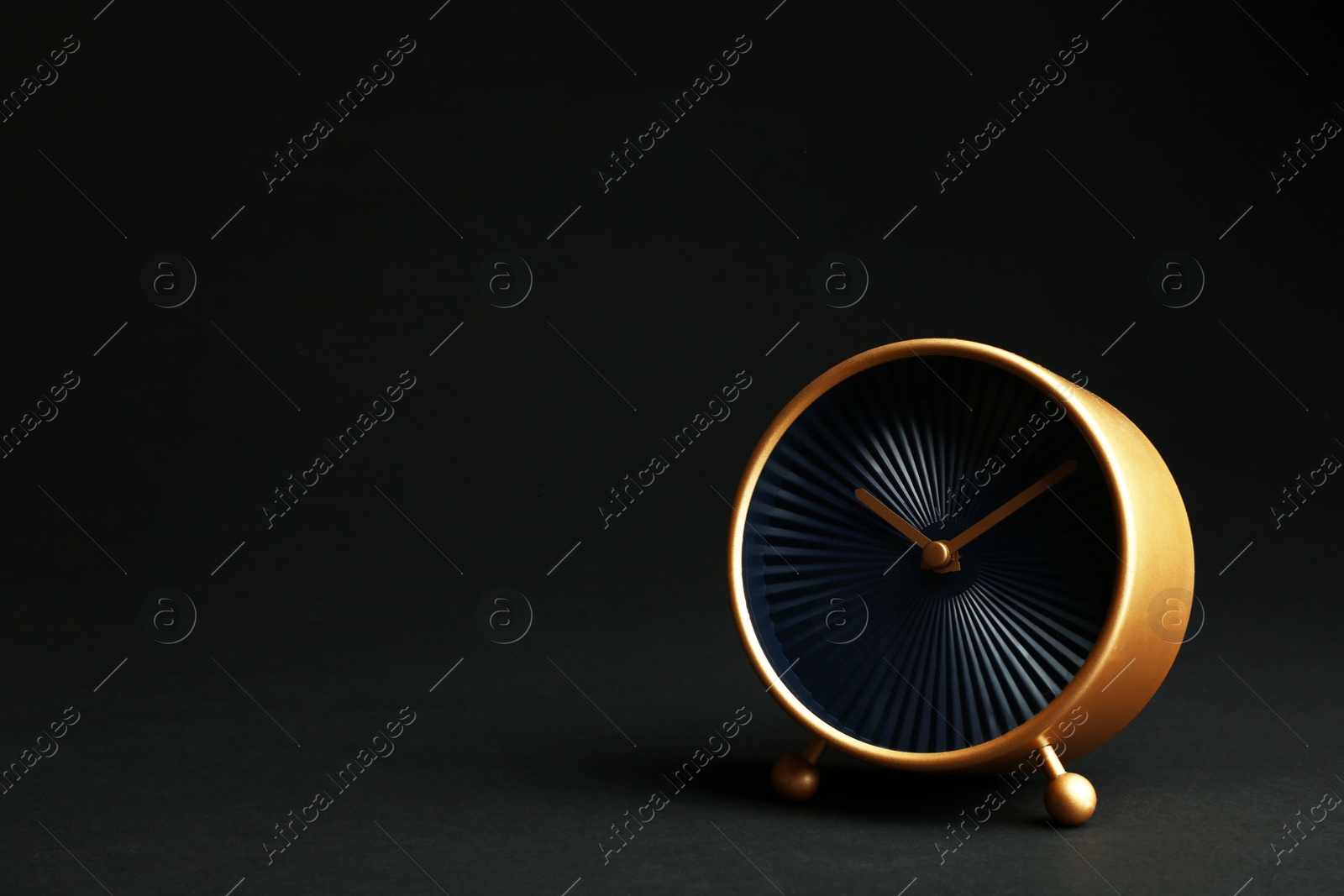 Photo of Golden alarm clock on black background. Space for text