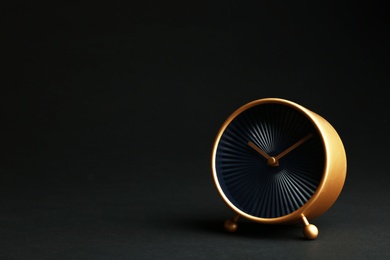 Photo of Golden alarm clock on black background. Space for text