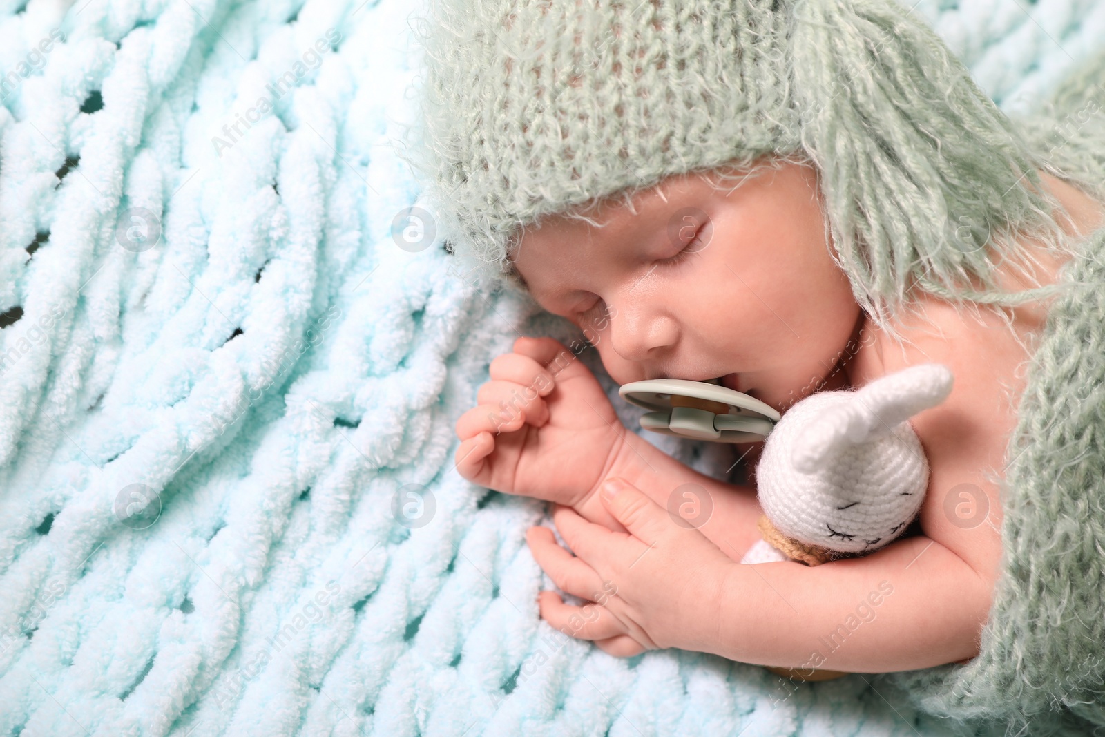 Photo of Cute newborn baby with pacifier sleeping on light blue blanket, top view. Space for text