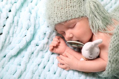 Photo of Cute newborn baby with pacifier sleeping on light blue blanket, top view. Space for text