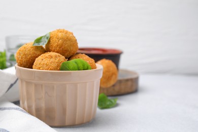 Photo of Bowl of delicious fried tofu balls with basil on white table, space for text