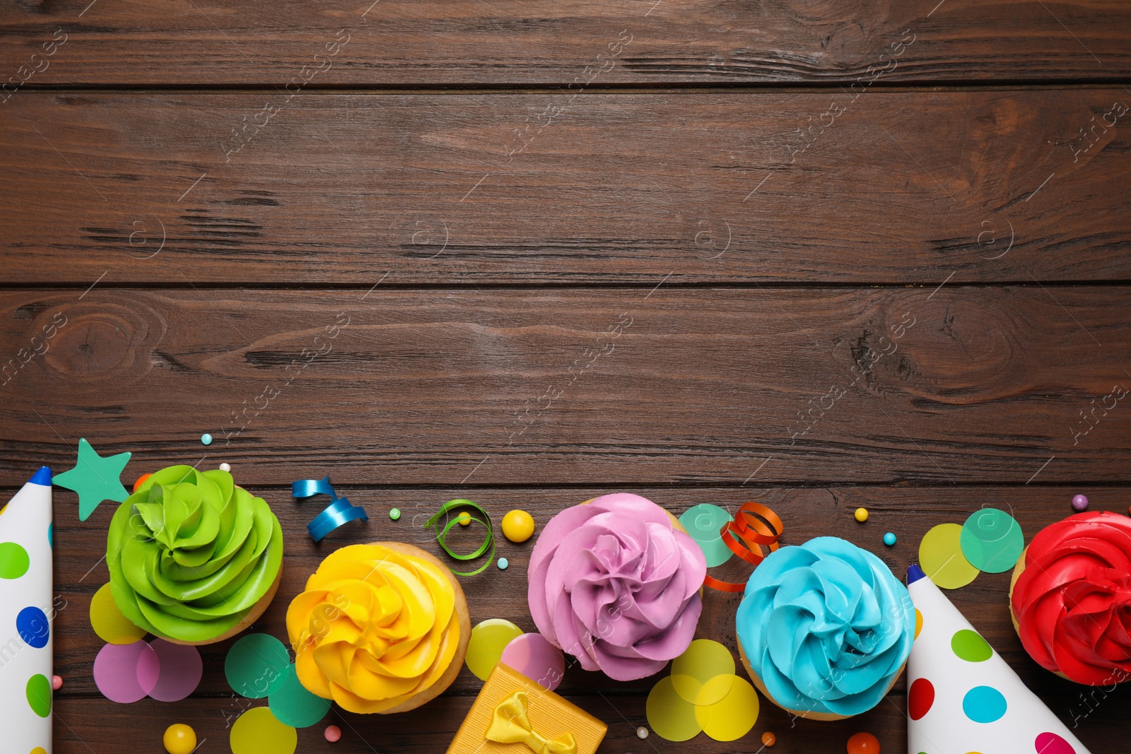 Photo of Flat lay composition with colorful birthday cupcakes on wooden table. Space for text