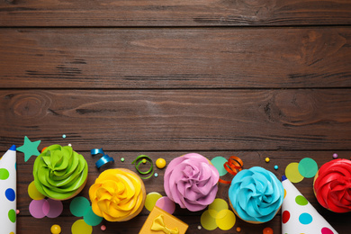 Flat lay composition with colorful birthday cupcakes on wooden table. Space for text