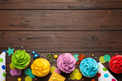 Photo of Flat lay composition with colorful birthday cupcakes on wooden table. Space for text