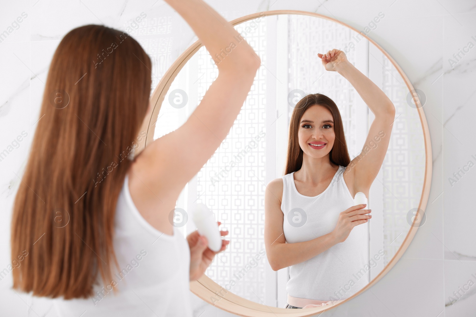 Photo of Beautiful young woman applying deodorant in bathroom