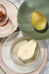 Photo of Stylish ceramic plates, glass and pears on white marble table, flat lay