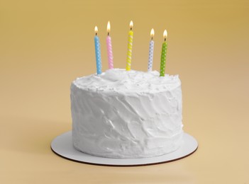 Photo of Delicious cake with cream and burning candles on yellow background