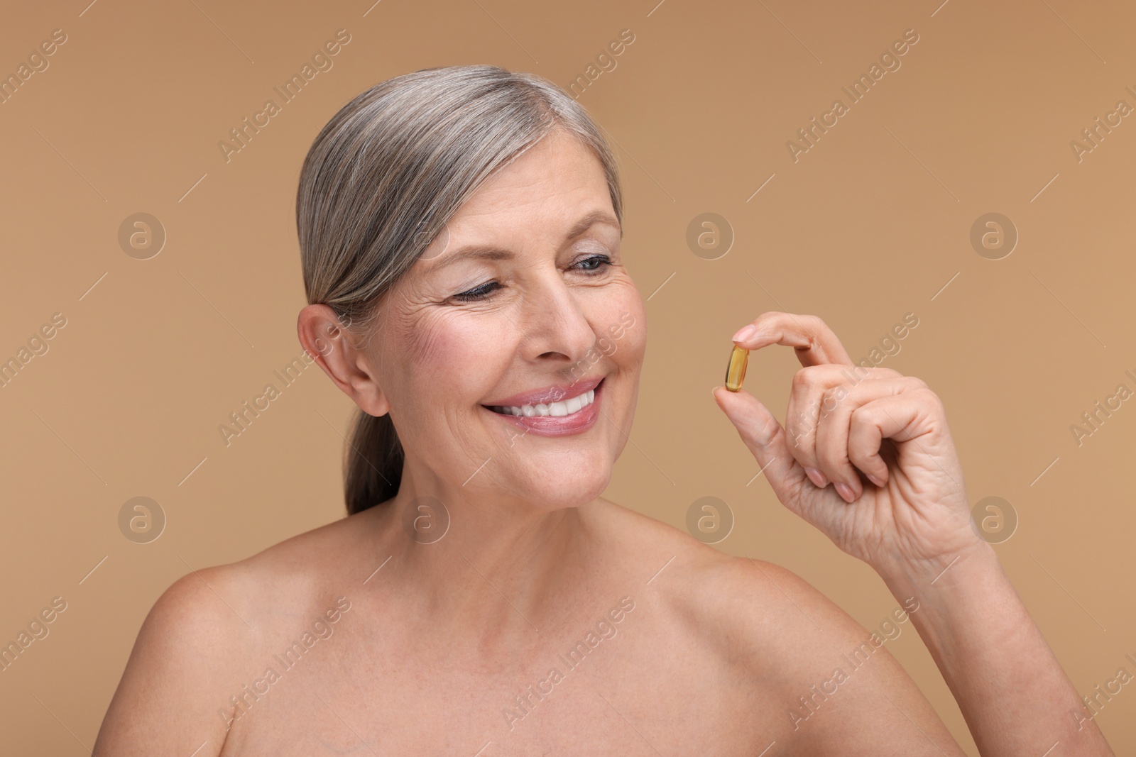 Photo of Beautiful woman with vitamin capsule on beige background