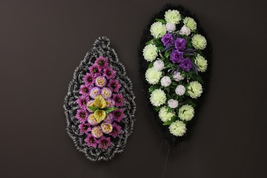 Funeral wreaths of plastic flowers hanging on dark grey wall