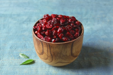 Photo of Wooden bowl with cranberries on table. Dried fruit as healthy snack