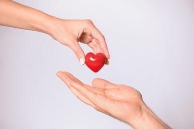 Photo of Woman giving red heart to man on white background, closeup. Donation concept