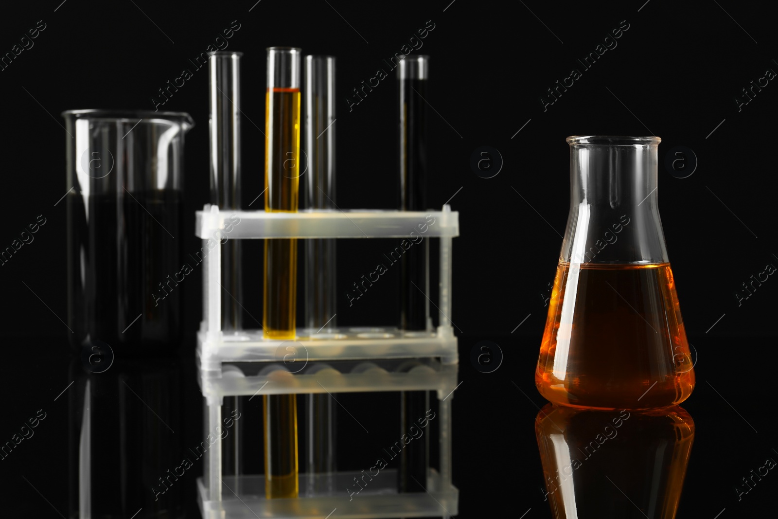 Photo of Laboratory glassware with different types of oil on black background, closeup