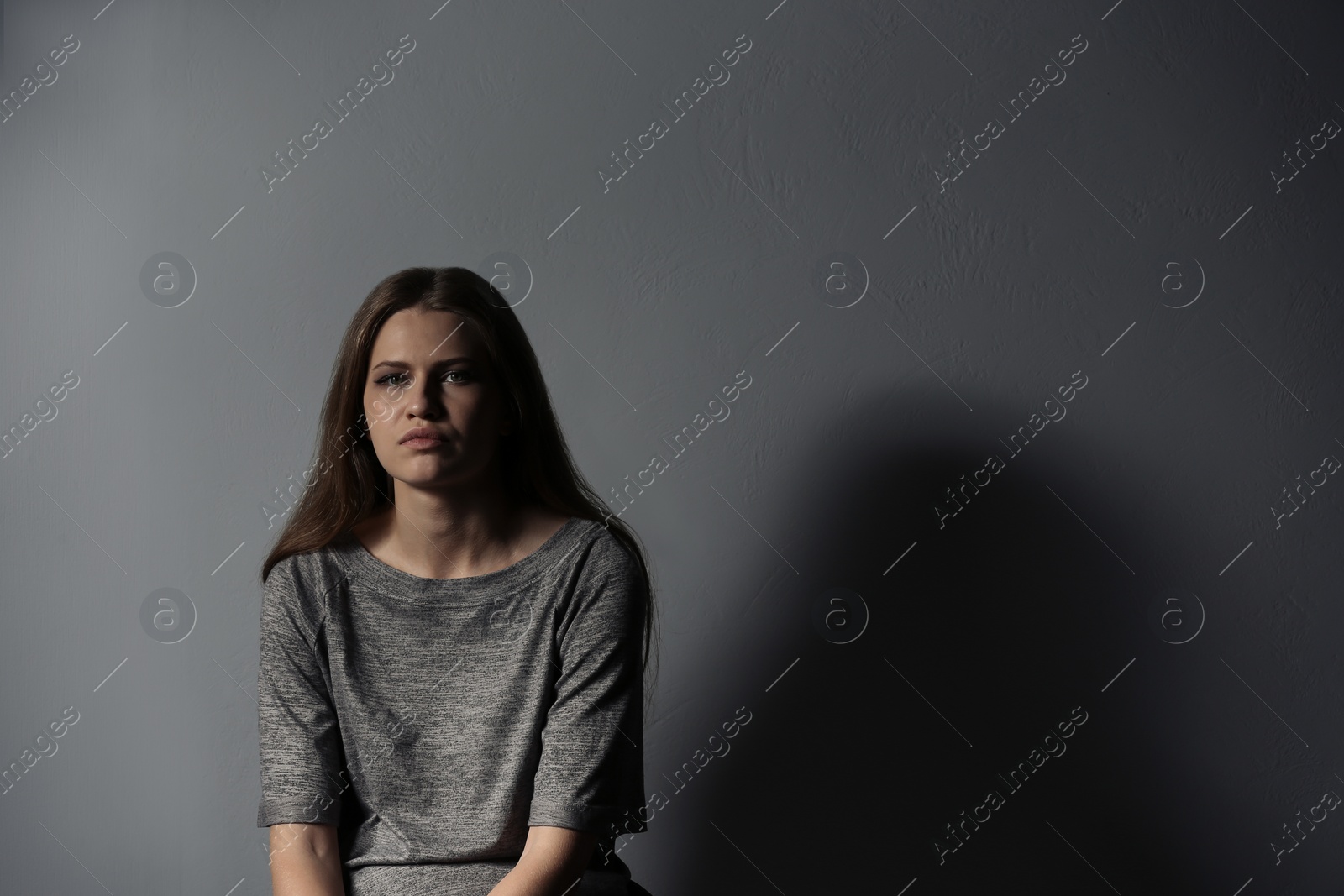 Photo of Depressed young woman on gray background