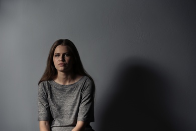 Depressed young woman on gray background