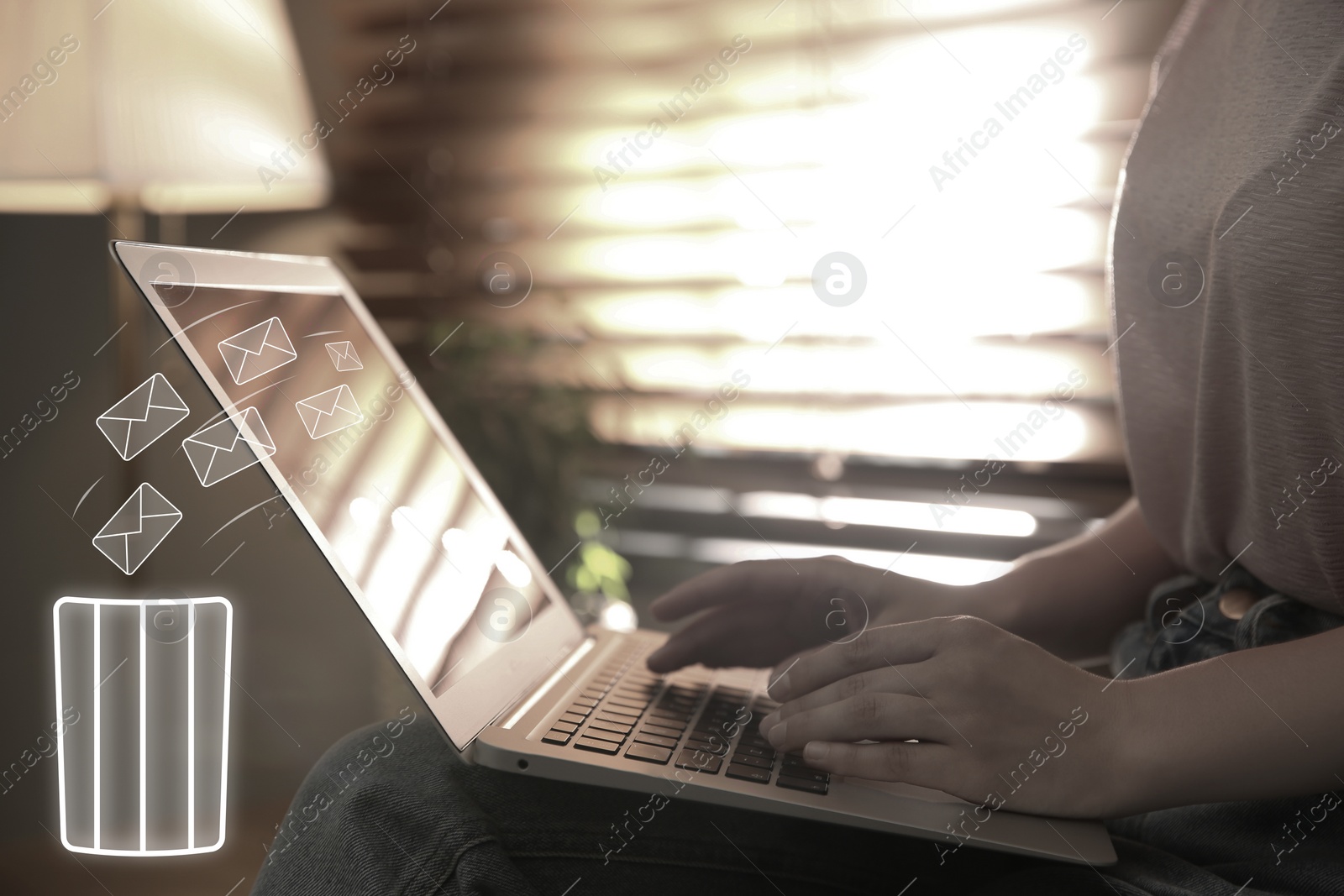 Image of Woman working at home, closeup. Envelopes flying from laptop into trash bin, illustration of spam removing