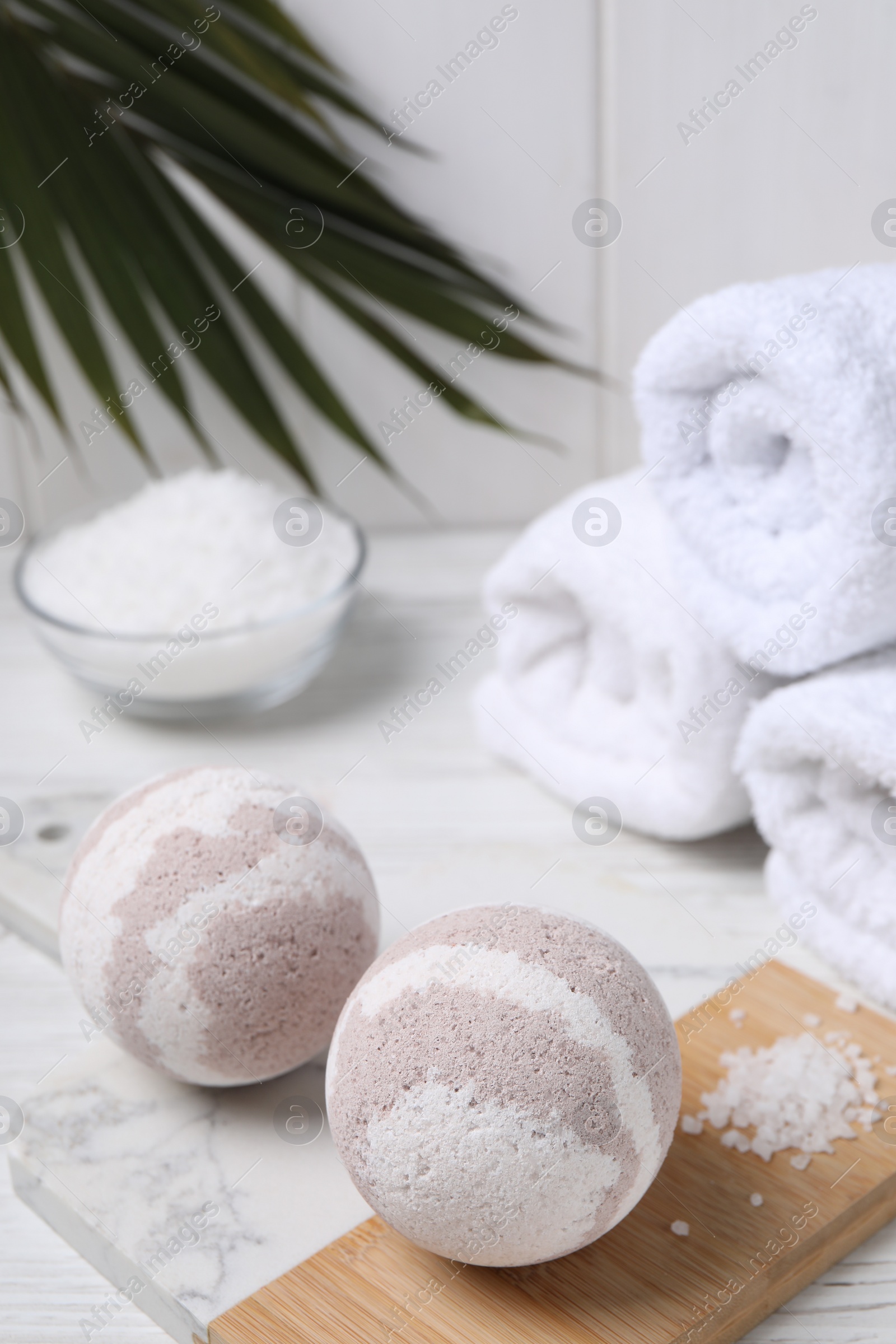 Photo of Bath bombs, sea salt and rolled towels on white wooden table