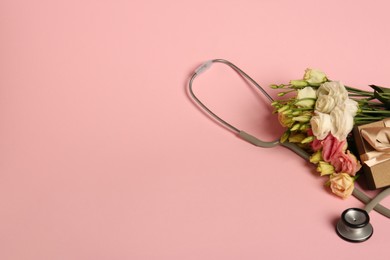 Stethoscope, gift box and eustoma flowers on pink background, space for text. Happy Doctor's Day