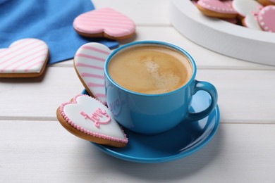 Photo of Delicious heart shaped cookies and cup of coffee on white wooden table