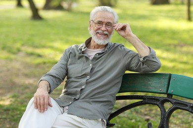 Photo of Portrait of happy grandpa with glasses on bench in park