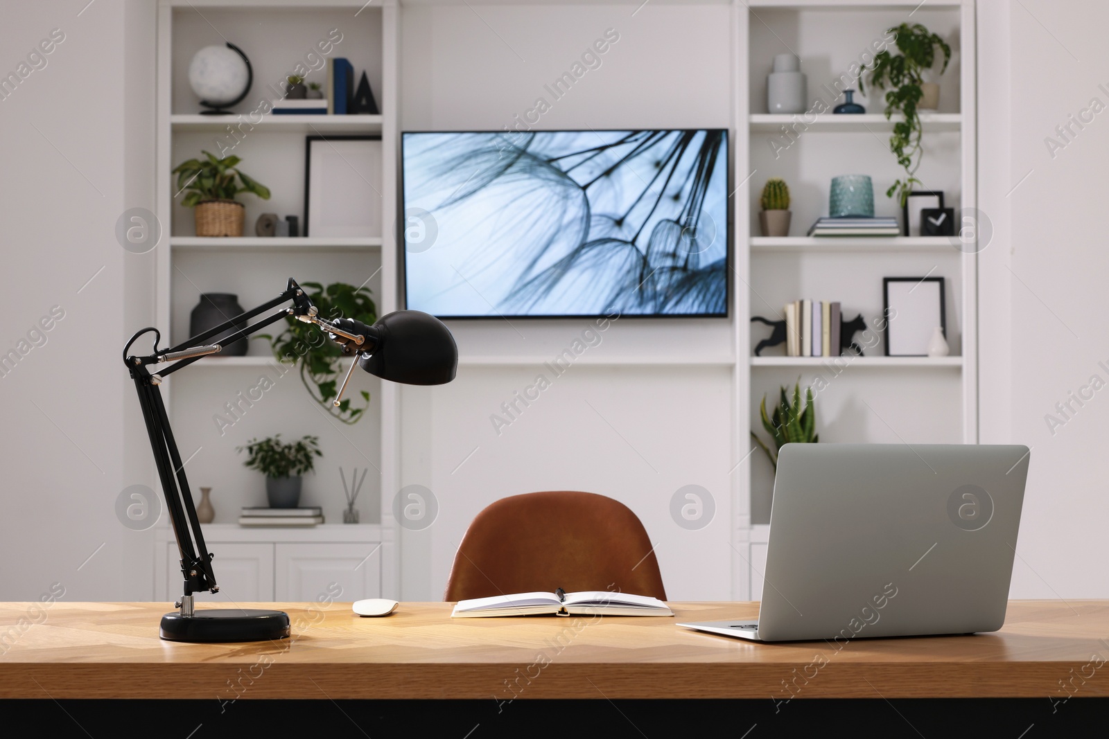 Photo of Cosy workplace with laptop near tv area. Interior design