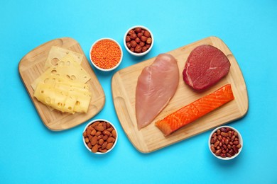 Different fresh products on light blue background, flat lay. Sources of essential amino acids