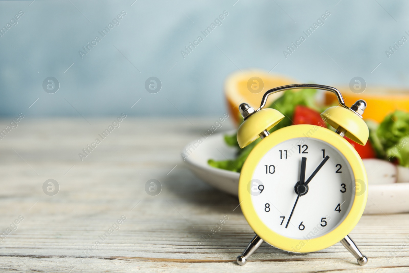 Photo of Alarm clock and healthy food on white wooden table, space for text. Meal timing concept