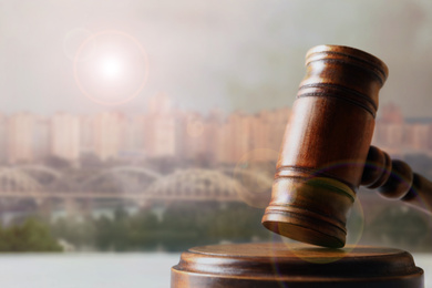 Image of Judge's gavel against beautiful cityscape, closeup. Space for text 