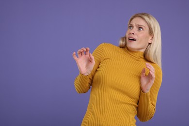 Portrait of surprised woman on violet background, space for text