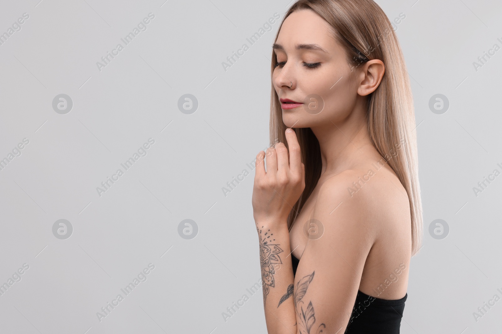 Photo of Portrait of beautiful tattooed woman on light background, space for text