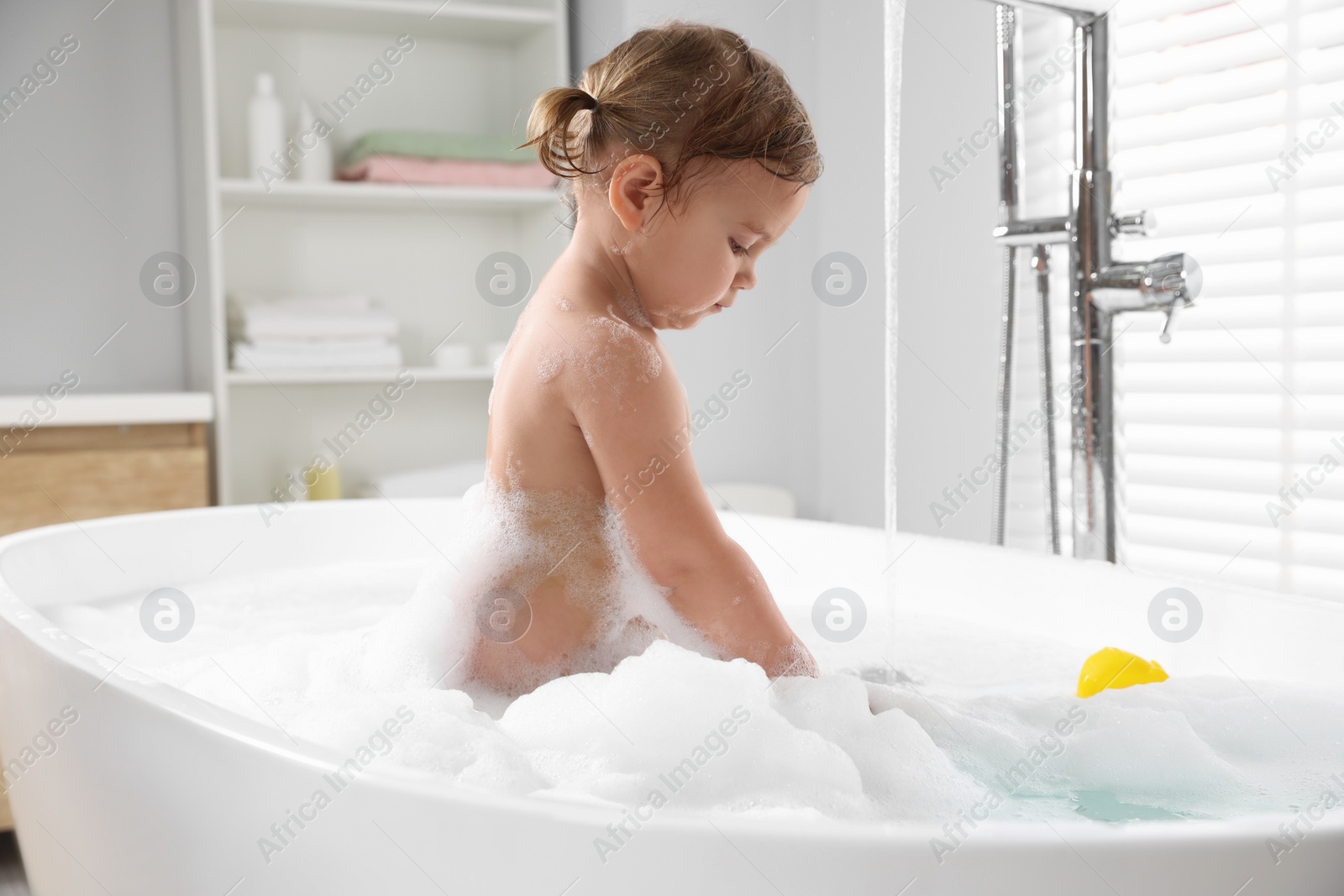 Photo of Cute little girl in foamy bath at home