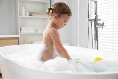 Photo of Cute little girl in foamy bath at home