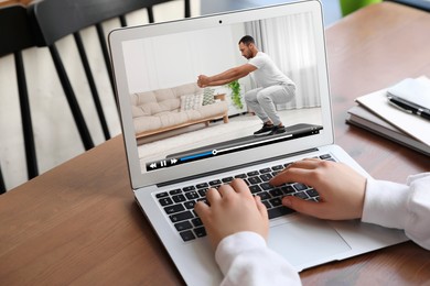 Image of Woman watching morning exercise video on laptop at table, closeup