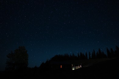 Photo of Beautiful view of house near dark forest under starry sky at night