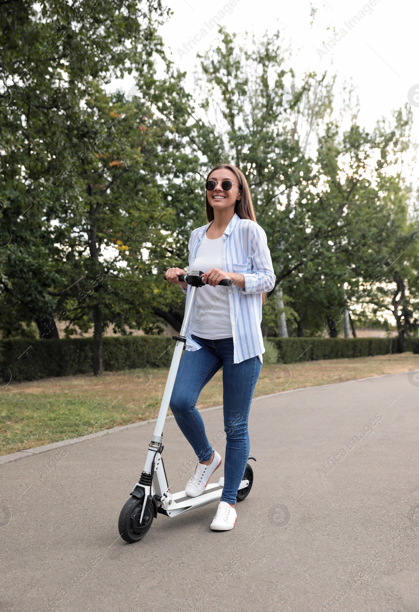 Photo of Young woman with electric kick scooter in park