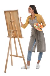 Photo of Young woman drawing on easel against white background