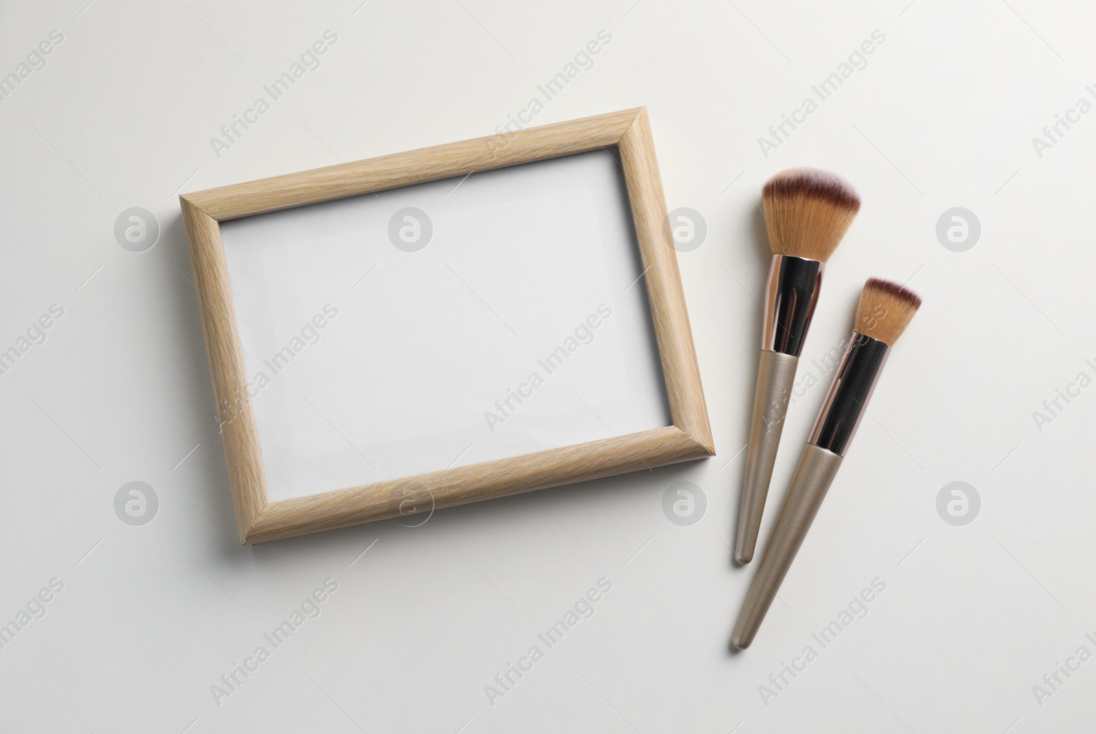 Photo of Blank board with makeup brushes on white background, flat lay. Space for text