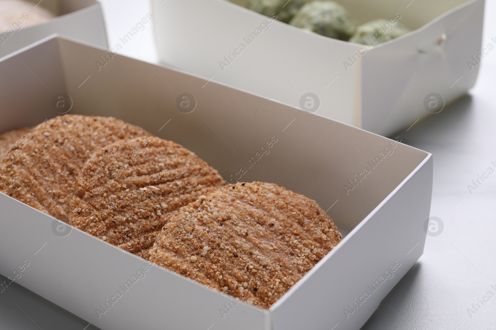 Photo of Raw vegan cutlets with breadcrumbs on white table, closeup