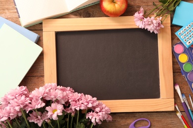 Blackboard, stationery and flowers on wooden table, flat lay with space for text. Teacher's Day