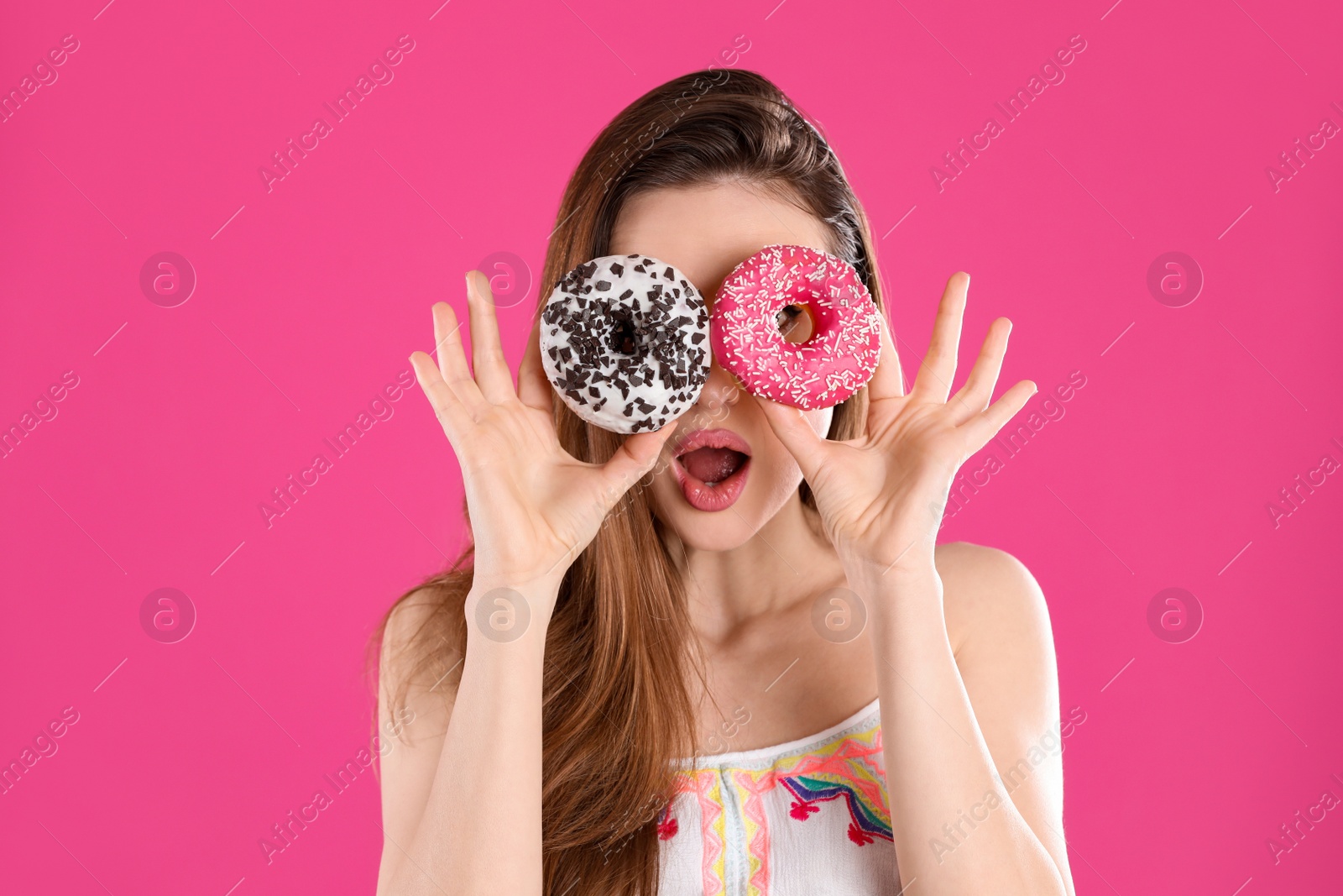 Photo of Beautiful young woman with donuts on pink background