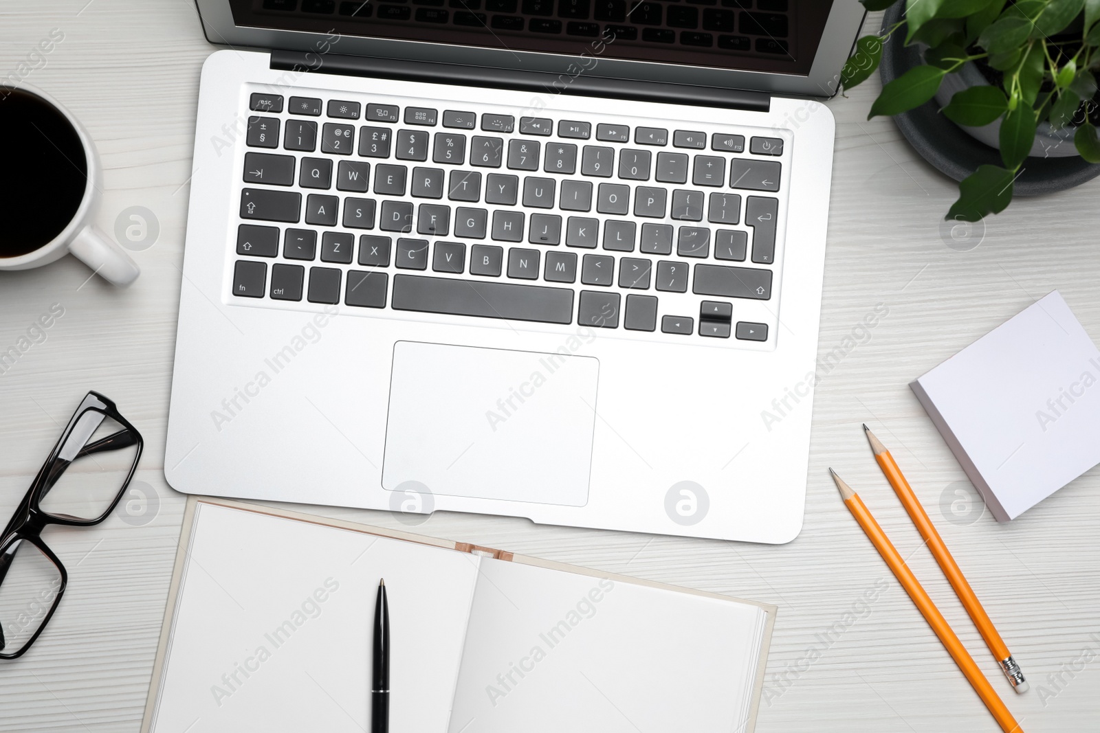 Photo of Modern laptop, office stationary, glasses and houseplant on white wooden table, flat lay