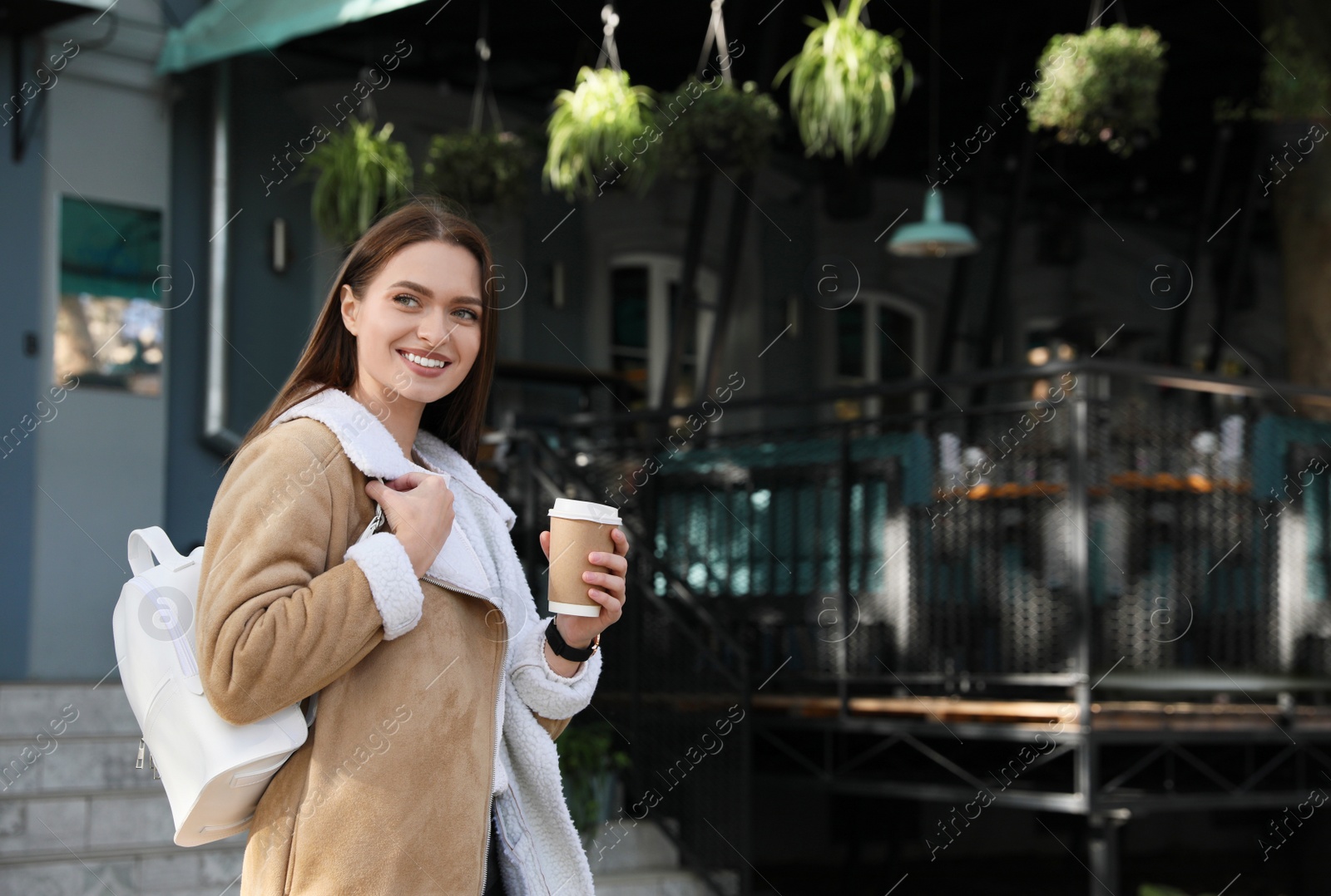 Photo of Young woman with stylish white backpack and cupdrink on city street, space for text