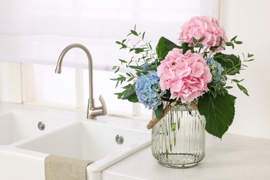 Photo of Beautiful hortensia flowers in vase on kitchen counter