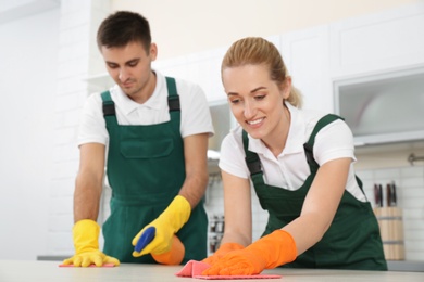 Photo of Team of janitors cleaning table in kitchen